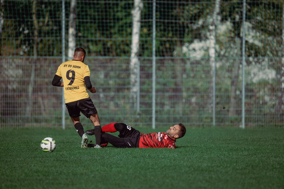 A footballer slides in to win the ball from an opponent during a match