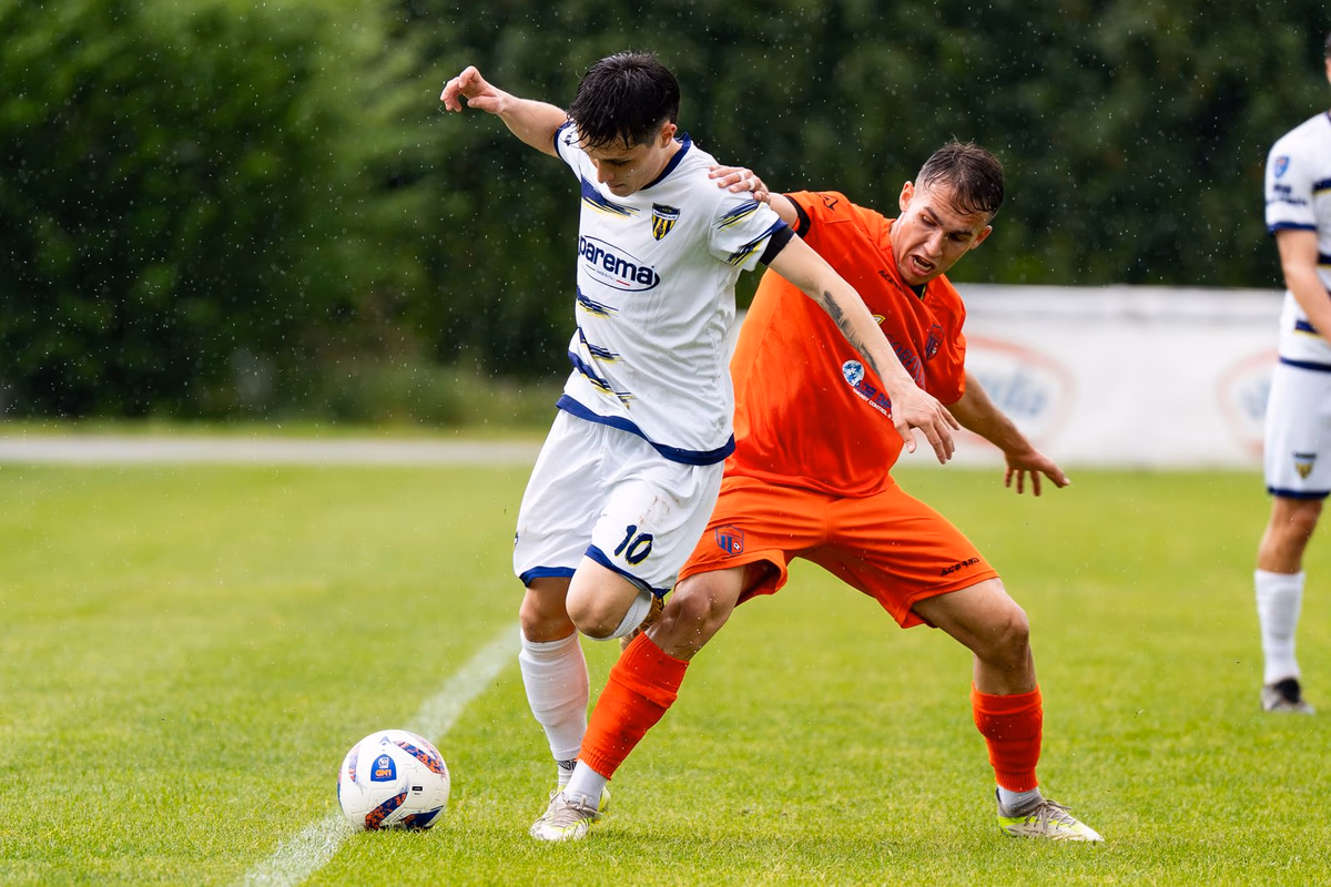 Two footballers pressed tight together battling for the ball near the touchline