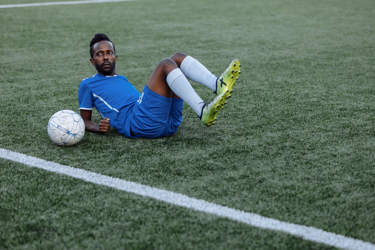 A footballer in blue lies on the pitch in dejection after the match