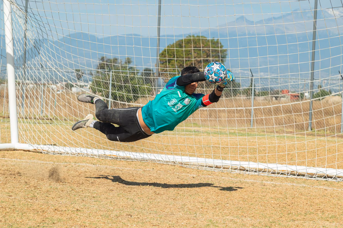 A goalkeeper diving to tip the ball away in a crucial save