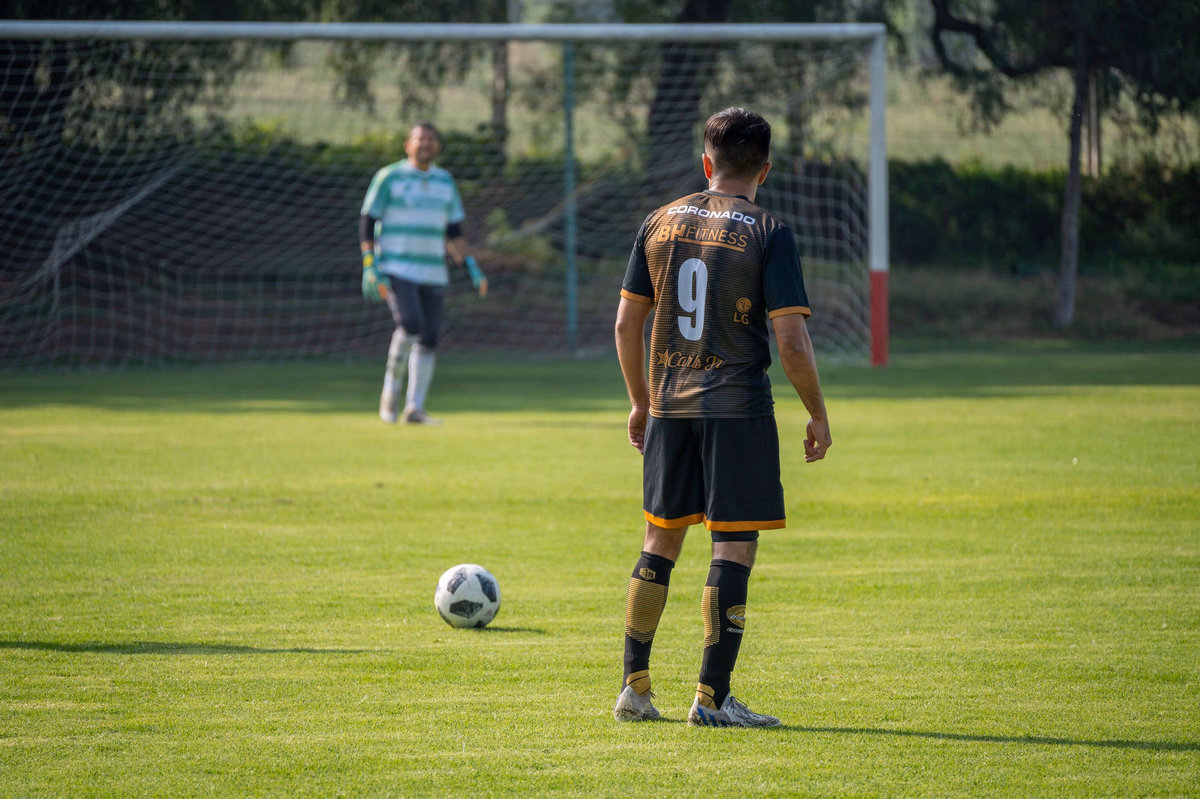 A number 9 stands over the ball at the penalty spot, facing the goalkeeper before the kick