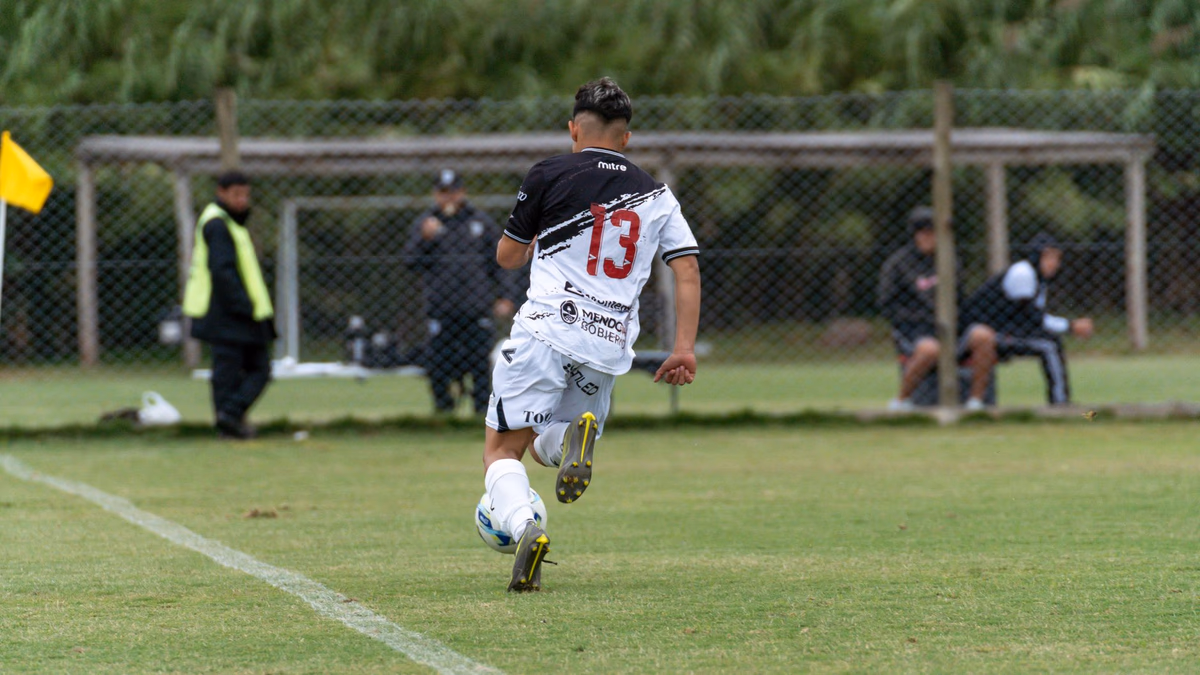 A footballer in a number 13 shirt sprinting forward with the ball on a fast break