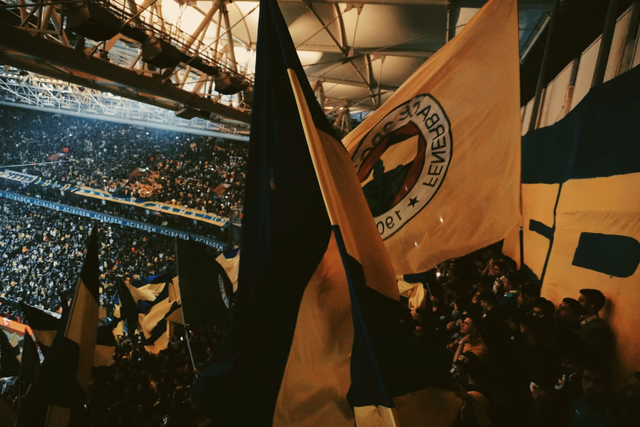 A packed stadium of football fans waving flags and roaring during a major match