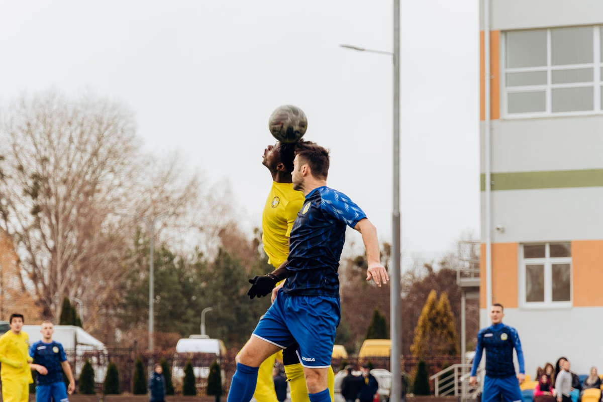 Two footballers jumping to contest a header in mid-air during a match