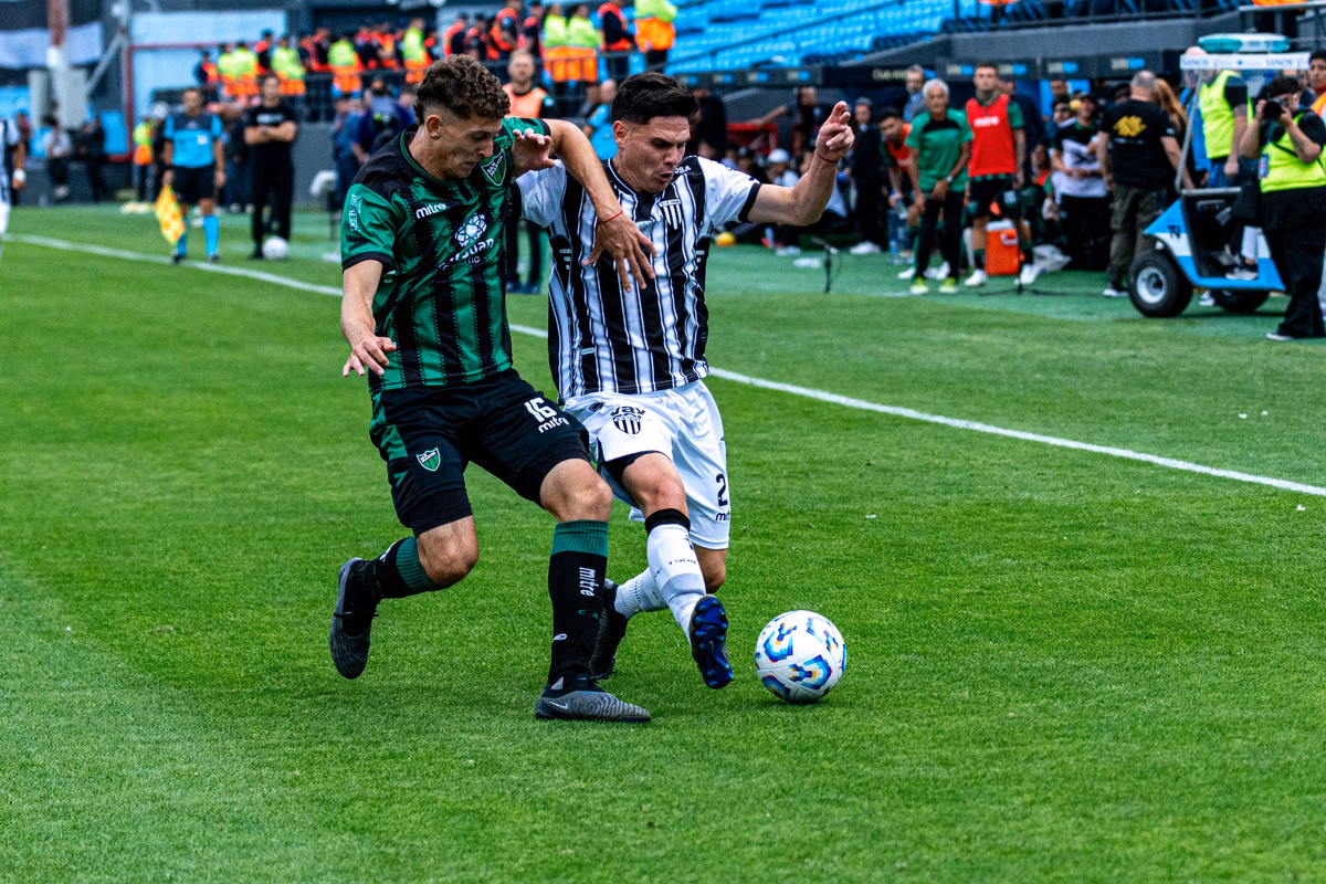 Two players from opposing teams battling fiercely for the ball in midfield
