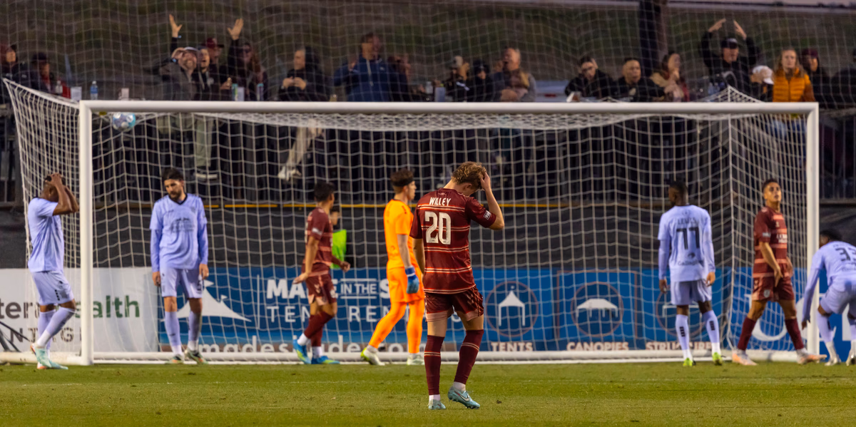 Footballers stand near the goal during a night match after a goalmouth scramble