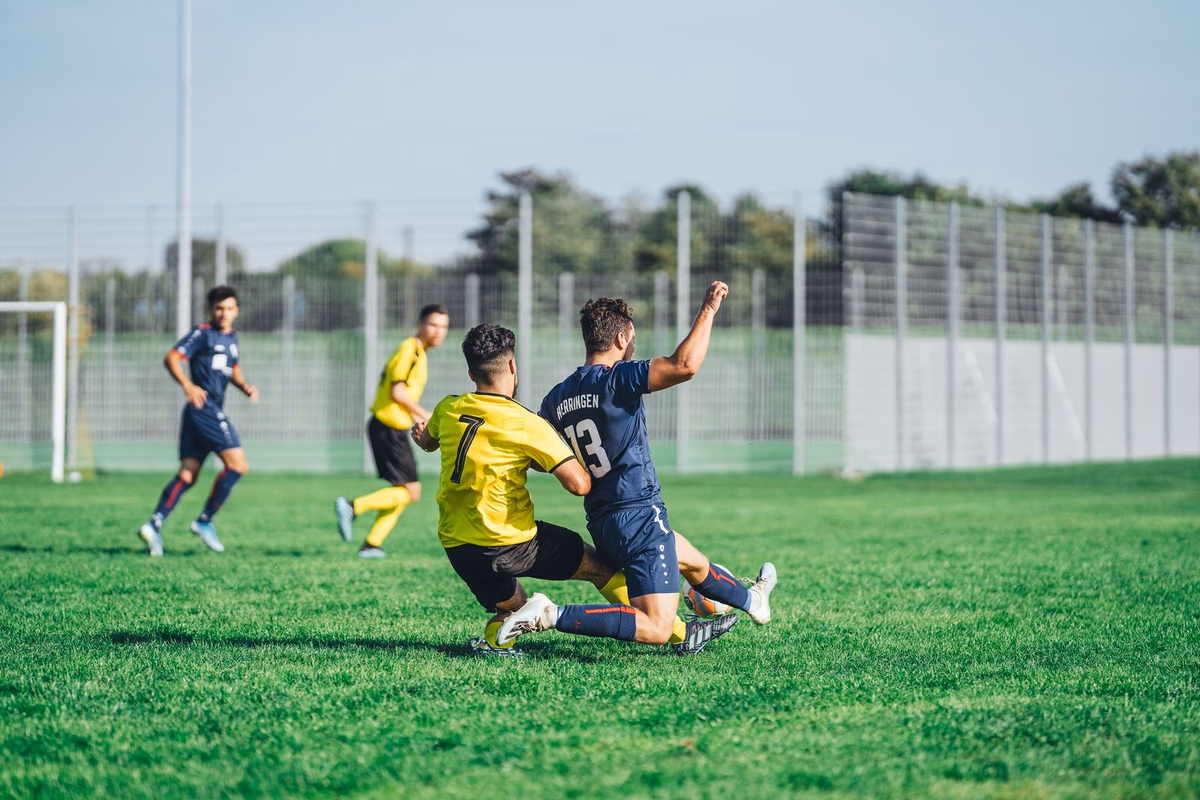A footballer making a sliding tackle on an opponent during a match