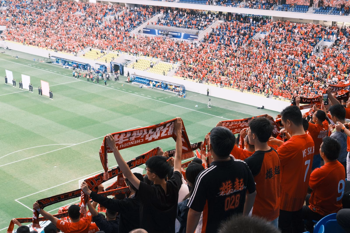 Football fans in a stadium raising scarves to support their team
