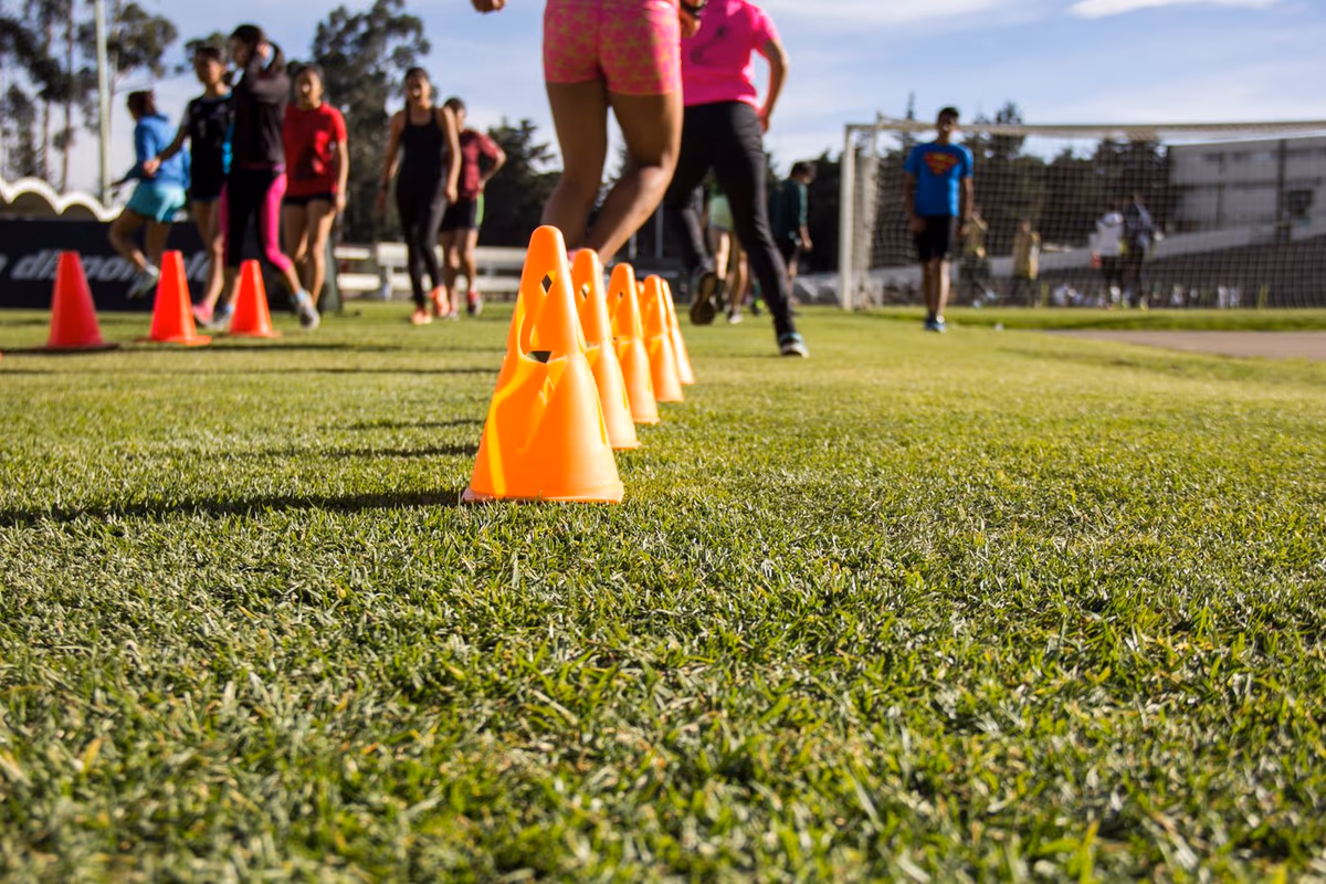 Footballers doing fitness drills with training cones on a pitch